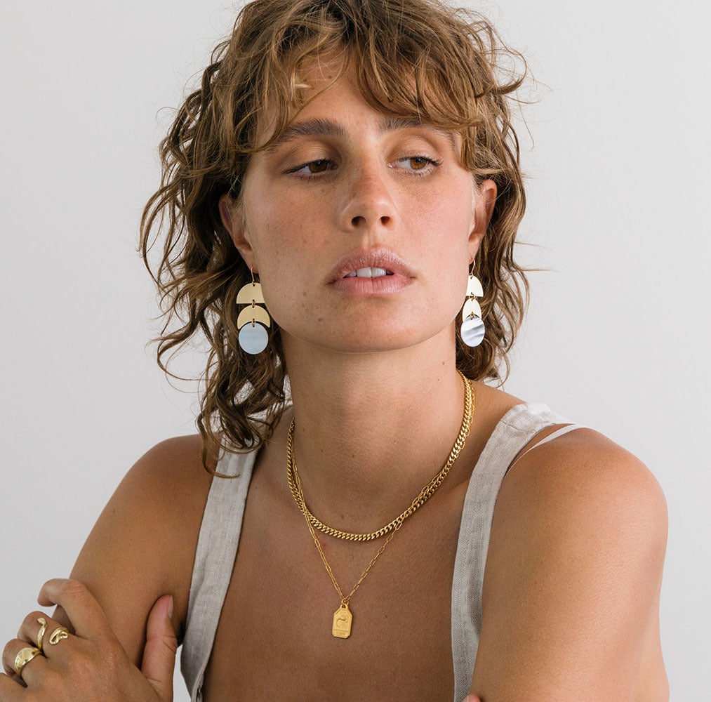 A woman wearing layered zodiac necklaces