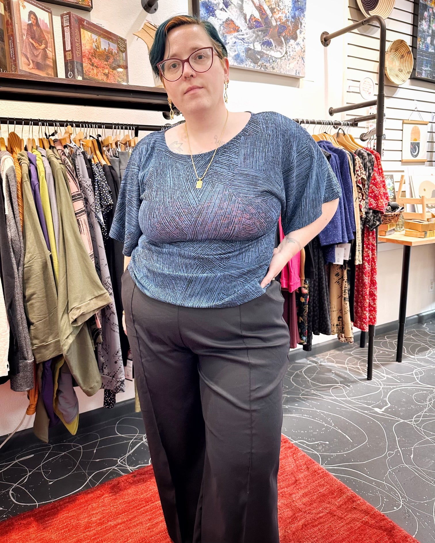 A woman standing in a blue top and black pants.