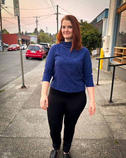 a woman standing in a cute blue knit top